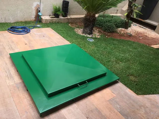 Tampa verde fechada sobre o deck de madeira, junto à borda da piscina