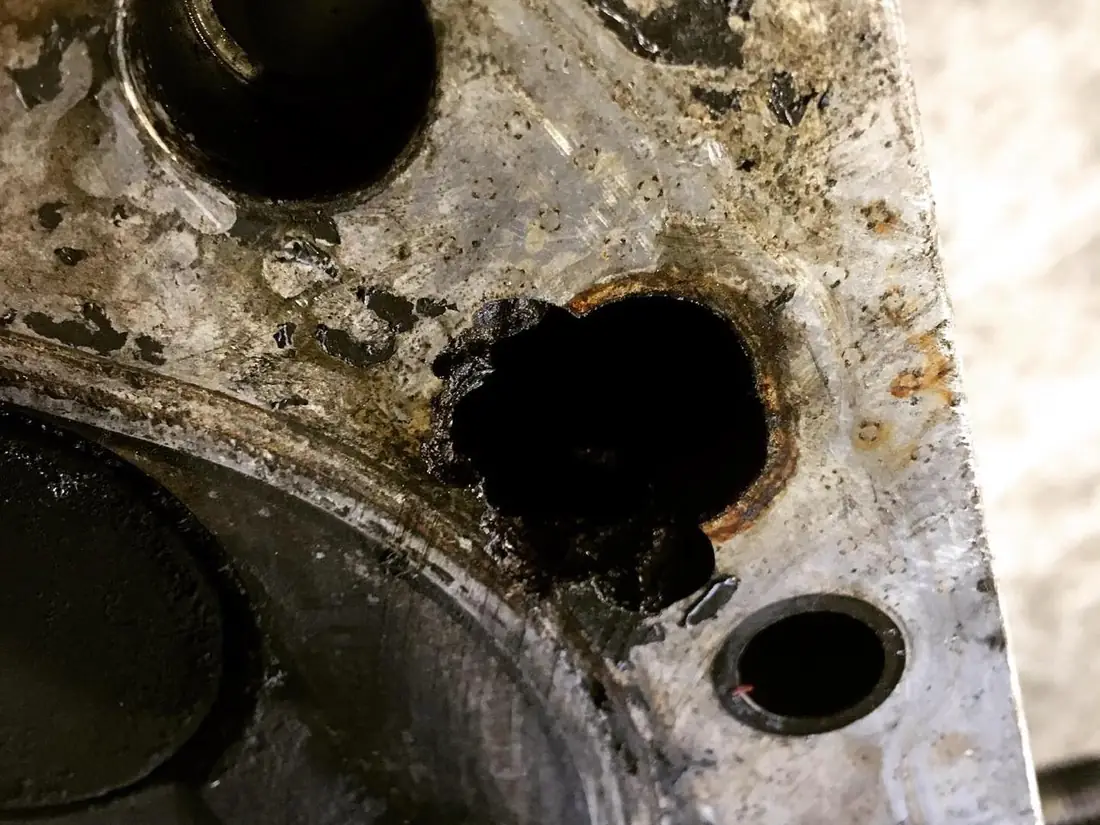 Cabeçote de alumínio antes do serviço: crosta escura, oxidação e um rombo aberto na câmara