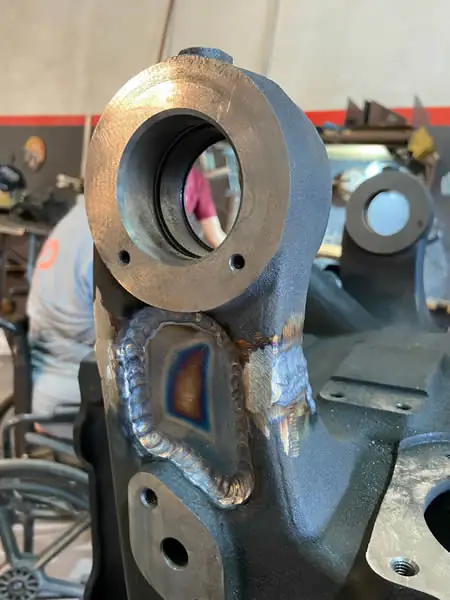 Peça de trator em ferro fundido, pintada de preto, com o furo usinado em primeiro plano