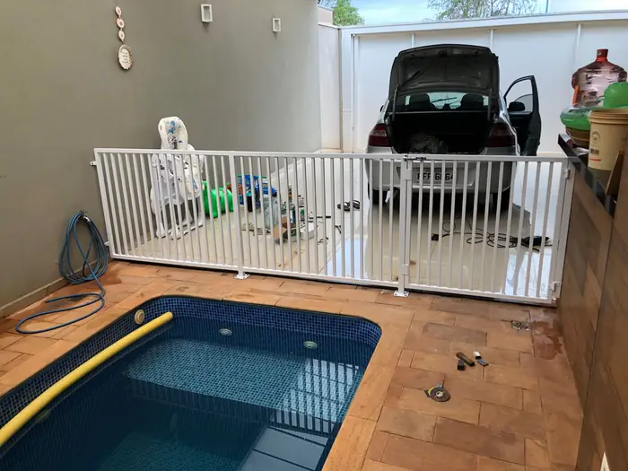 Gradil branco cercando a piscina, com a casa ao fundo