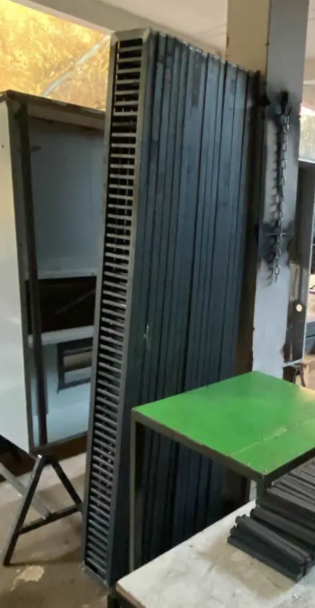 Grelha metálica apoiada ao lado de uma peça pintada de verde