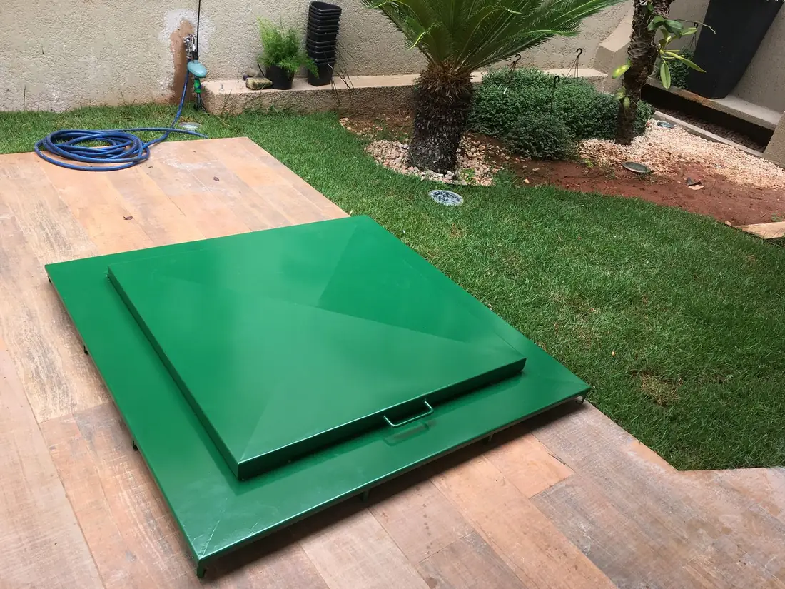 Tampa verde fechada sobre o deck de madeira, junto à borda da piscina